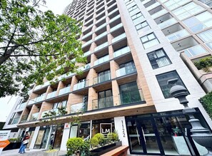A multi-story hotel with a modern design, featuring balconies, large windows, and a ground-level entrance with a sign. - Ocean View | Pool | Gym | A/C | Ravine (Lima)