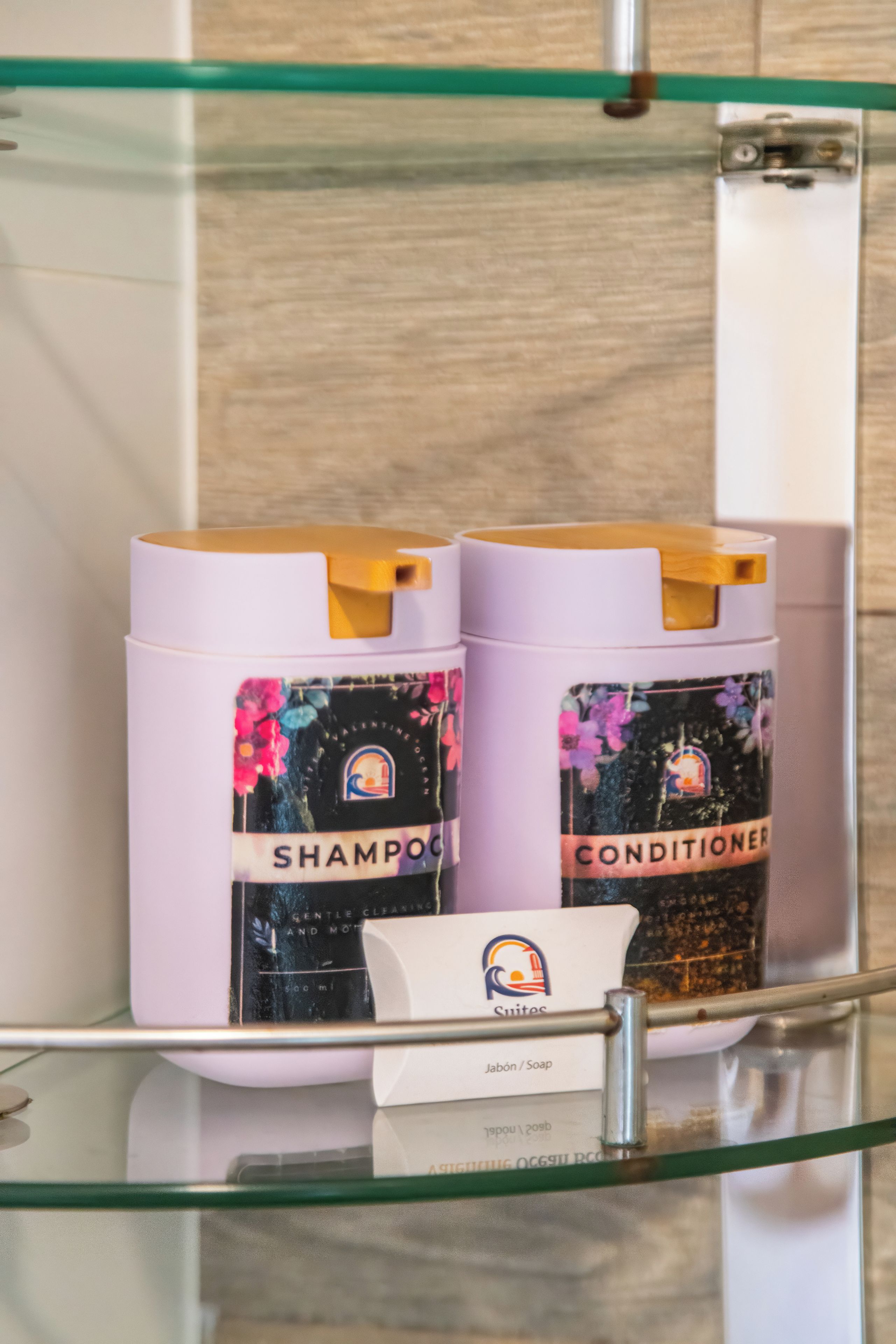 Une étagère de salle de bain avec deux bouteilles de shampoing et d’après-shampoing, et une petite bouteille de savon.