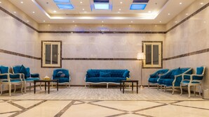 A spacious lobby with a blue sofa set, two armchairs, and a coffee table. - BARADIS LAND HOTEL (Makkah)