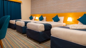 A hotel room with four beds arranged in a row, each with a headboard, pillows, and a bedside lamp. - BARADIS LAND HOTEL (Makkah)