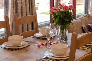 A dining table set with white plates, bowls, cutlery, and a vase with flowers. - 2 Bed in Staithes (oc-wa022) (Easington)