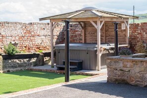 A gazebo with a hot tub, surrounded by a stone wall and a grassy area. - 2 Bed in Staithes (oc-wa022) (Easington)