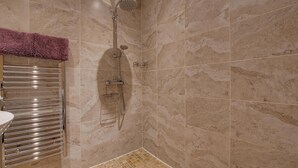 Casa de banho com chuveiro, um porta-toalhas e chão em azulejo.