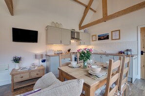A cozy kitchen with wooden beams, a dining table set for four, and a TV mounted on the wall. - 2 Bed in Staithes (oc-wa022) (Easington)