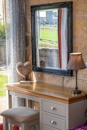 A wooden desk with a mirror, a lamp, and a heart-shaped decoration against a stone wall. - 2 Bed in Staithes (oc-wa022) (Easington)
