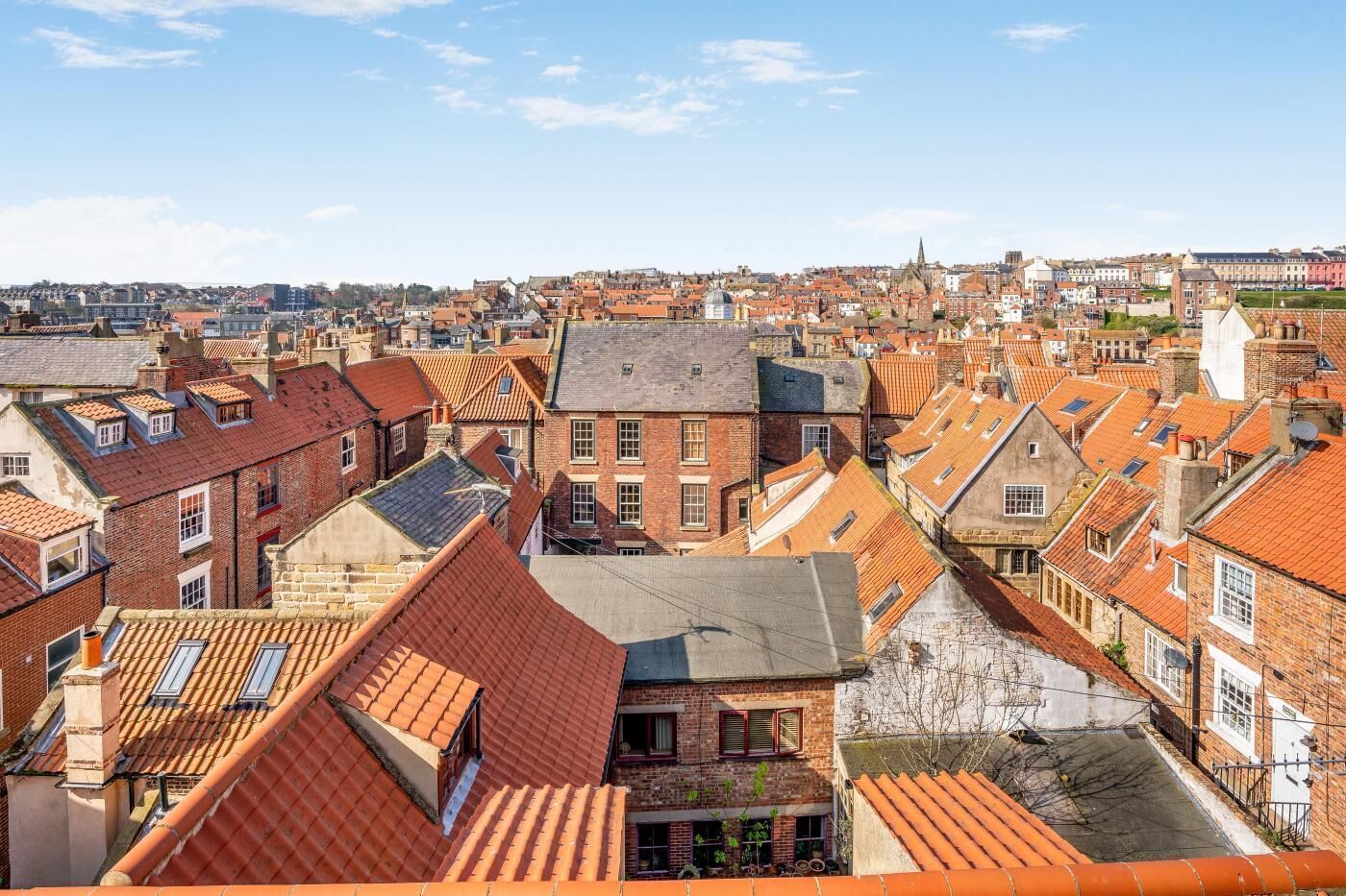 Une zone urbaine densément peuplée, caractérisée par des toits recouverts de tuiles rouges et des bâtiments en briques, ce qui rappelle une ville européenne historique.