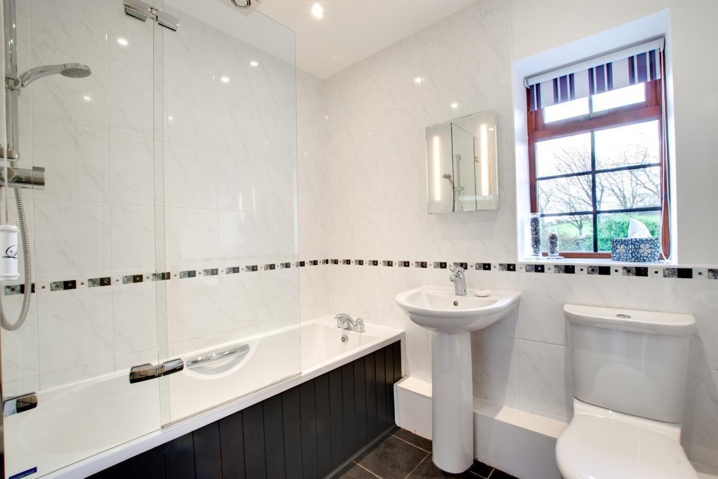 A modern bathroom with a glass-enclosed shower, a freestanding bathtub, a pedestal sink, and a toilet.
