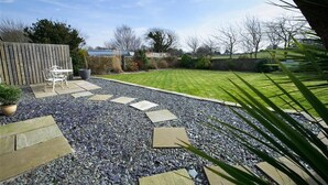 Ein Garten mit Kiesweg, Holzzaun und einer Bank.