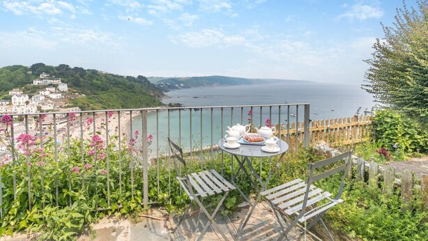 A balcony with a table set for tea, overlooking a coastal town and the sea. - 2 Bed in Looe (oc-l30026) (Looe)