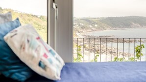 A balcony with a view of a coastal landscape, a cushion, and a window. - 2 Bed in Looe (oc-l30026) (Looe)