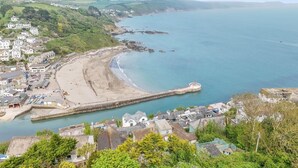 A coastal town with a sandy beach, a pier, and residential buildings. - 2 Bed in Looe (oc-l30026) (Looe)