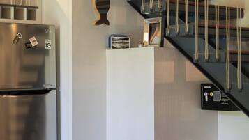 Una cocina con un refrigerador de acero inoxidable, una mesa de vidrio y una escalera con barandilla negra.