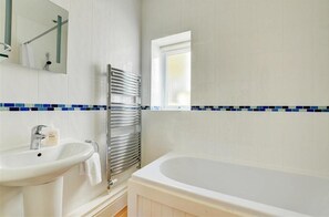 A bathroom with a white sink, a mirror, a towel rack, and a bathtub. - 1 Bed in Looe (oc-l30004) (Looe)