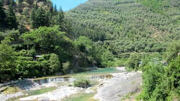 A natural landscape with a river, rocky terrain, and dense forest.