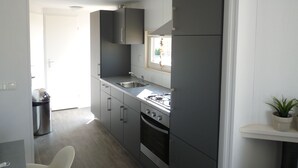 Een moderne keuken met grijze kastjes, een roestvrijstalen spoelbak en een gasfornuis.