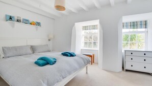 Quarto com cama, penteadeira, janela e decoração nas paredes.