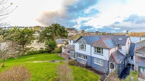 A coastal house with a well-maintained lawn, a large tree, and a view of the sea. - 5 Bed in Polruan (oc-ccmead) (Fowey)