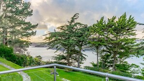 A scenic view from a balcony overlooking a body of water, with lush greenery and a stone pathway. - 5 Bed in Polruan (oc-ccmead) (Fowey)