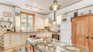 Una cucina moderna con un tavolo da pranzo in vetro, mobili in legno e un'ampia porta in legno.
