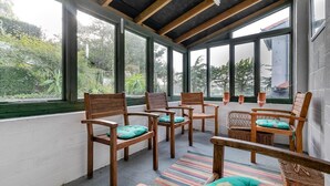 A sunroom with wooden chairs and a wicker chair, large windows, and a colorful striped rug. - 2 Bed in Polruan (oc-cgart2) (Fowey)