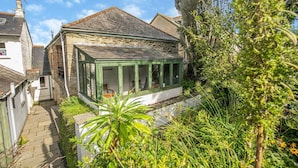 A traditional stone house with a conservatory, surrounded by lush greenery. - 2 Bed in Polruan (oc-cgart2) (Fowey)