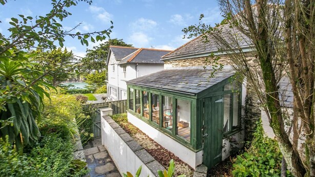 A house with a conservatory, surrounded by lush greenery and a view of a body of water. - 2 Bed in Polruan (oc-cgart2) (Fowey)