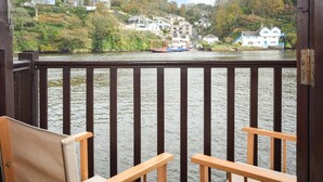 Una terraza de madera con vista a un río y casas al fondo.