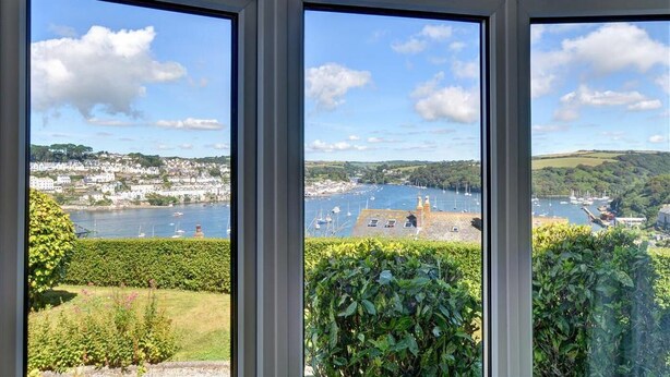 A view from a window overlooking a coastal town with a harbor, boats, and greenery. - 3 Bed in Fowey (oc-clenti) (Fowey)