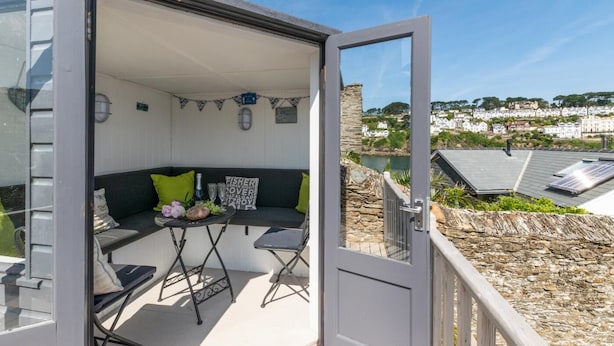 A covered outdoor seating area with a table, chairs, and a view of a coastal town. - 2 Bed in Fowey (oc-ccgree) (Fowey)