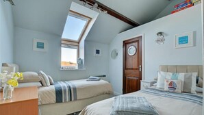 A bedroom with two beds, a skylight, a wooden door, and a view of the sea. - 2 Bed in Fowey (oc-ccgree) (Fowey)
