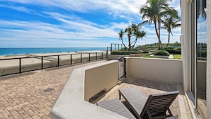 A balcony with a view of the beach and palm trees.
