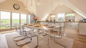 Eine moderne Küche mit Essbereich, großen Fenstern und Blick ins Freie.