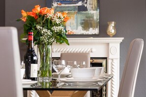 A dining table set with white plates, glasses, and a vase with flowers. - 4 Bed in Looe (oc-l30016) (Looe)