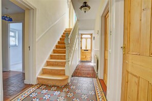 A staircase with a patterned carpet leading to a door. - 4 Bed in Looe (oc-l30016) (Looe)