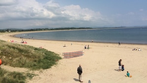 A beach with people relaxing and a blanket on the sand. - 2 Bed in Pwllheli (oc-wag303) (Y Ffôr)