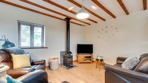 A modern living room with leather sofas, a black wood-burning stove, a flat-screen TV, and a window with blinds. - 2 Bed in Y Felinheli (oc-wag431) (Y Felinheli)