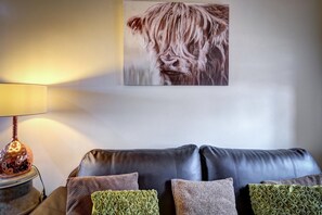 A living room with a black leather sofa, patterned cushions, a lamp, and a wall-mounted artwork. - 2 Bed in Y Felinheli (oc-wag431) (Y Felinheli)