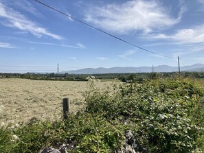 A rural landscape with a field, a wooden fence, and distant mountains under a clear sky. - 2 Bed in Y Felinheli (oc-wag431) (Y Felinheli)