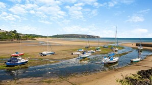 A coastal scene with boats moored along a sandy beach, a calm sea, and a clear sky. - 3 Bed in Abersoch (oc-4ynysf) (Abersoch)