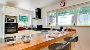 A modern kitchen with a wooden island, stainless steel appliances, and a large window with a view of greenery. - 2 Bed in Pwllheli (oc-wag560) (Pwllheli)
