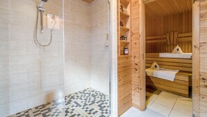 A sauna room with wooden walls and benches, a glass shower enclosure, and a tiled floor. - 4 Bed in Aberdaron (oc-fl055) (Aberdaron)
