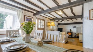 A dining area with a wooden table set for a meal, a fireplace, and a view of the outdoors. - 4 Bed in Aberdaron (oc-fl055) (Aberdaron)