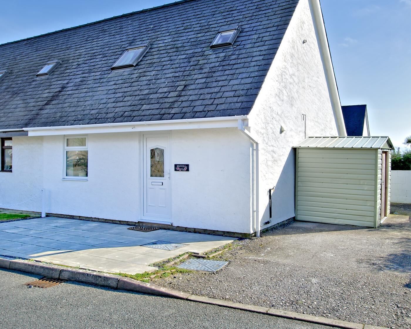 A single-story building with a sloped roof, a white exterior, and a small garage door.