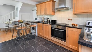 Een moderne keuken met houten kastjes, een zwart aanrecht en een roestvrijstalen afzuigkap.