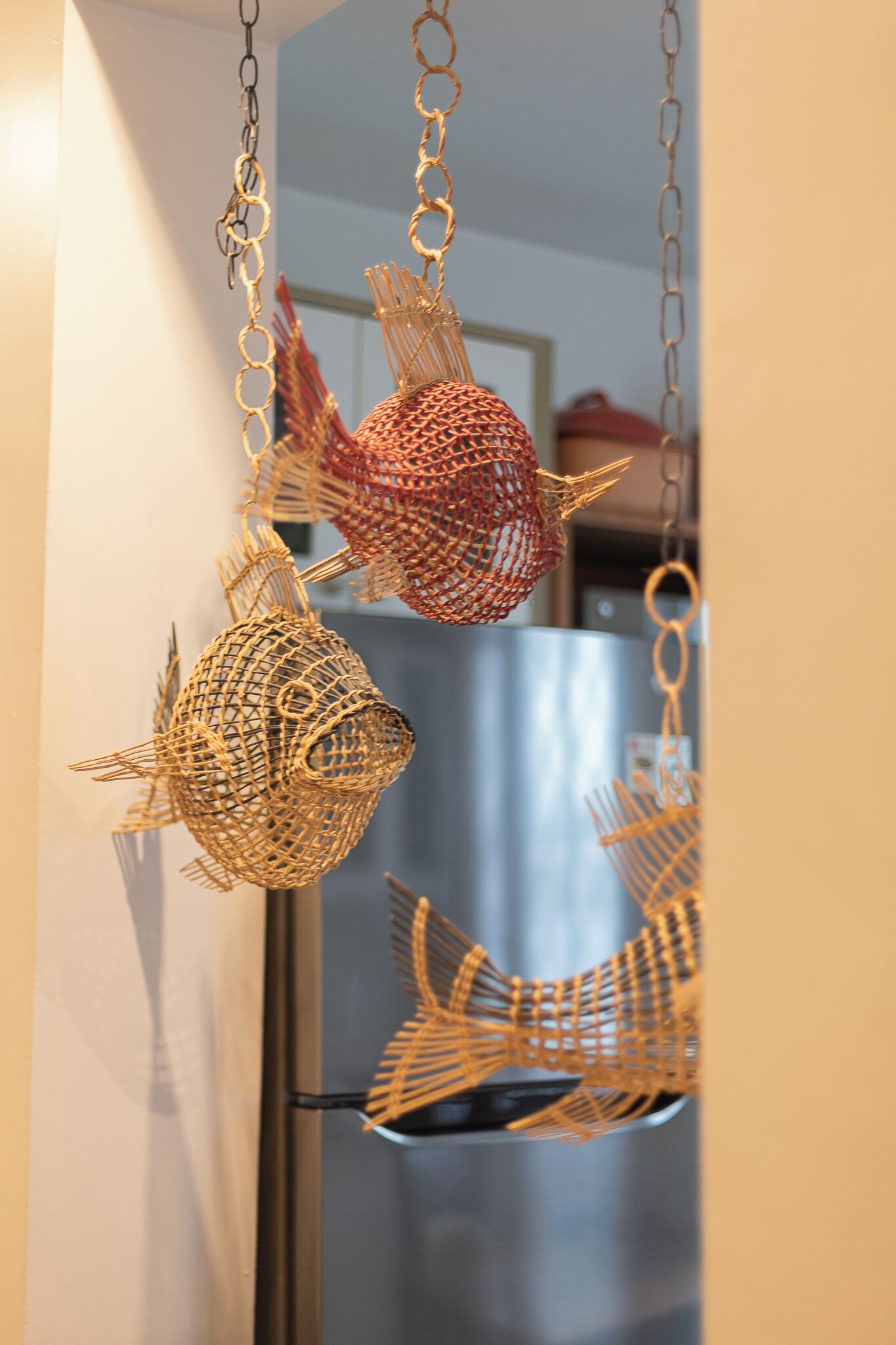 Une cuisine dotée d’un réfrigérateur en acier inoxydable et ornée de poissons décoratifs suspendus, faits de fil de fer.
