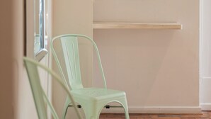 Ein Zimmer mit zwei hellgrünen Stühlen, einem gewebten Korb an der Wand und einem Holzboden.