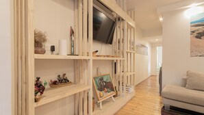 Ein modernes Wohnzimmer mit Holzregalen, einem Flachbildfernseher und einem beigefarbenen Sofa.