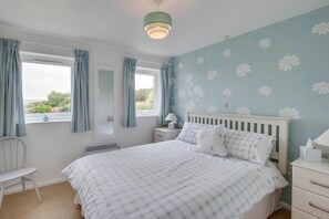 A bedroom with a bed, a nightstand, a chair, and a window with curtains. - 3 Bed in Pwllheli (oc-5ynysf) (Abersoch)