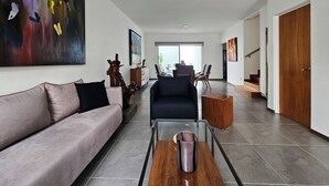 Een moderne woonkamer met een bank, salontafel en kunst aan de muren.