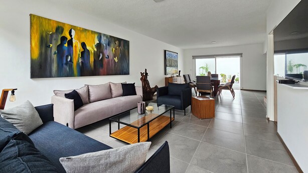 Een moderne woonkamer met een bank, salontafel en kunstwerk aan de wand.